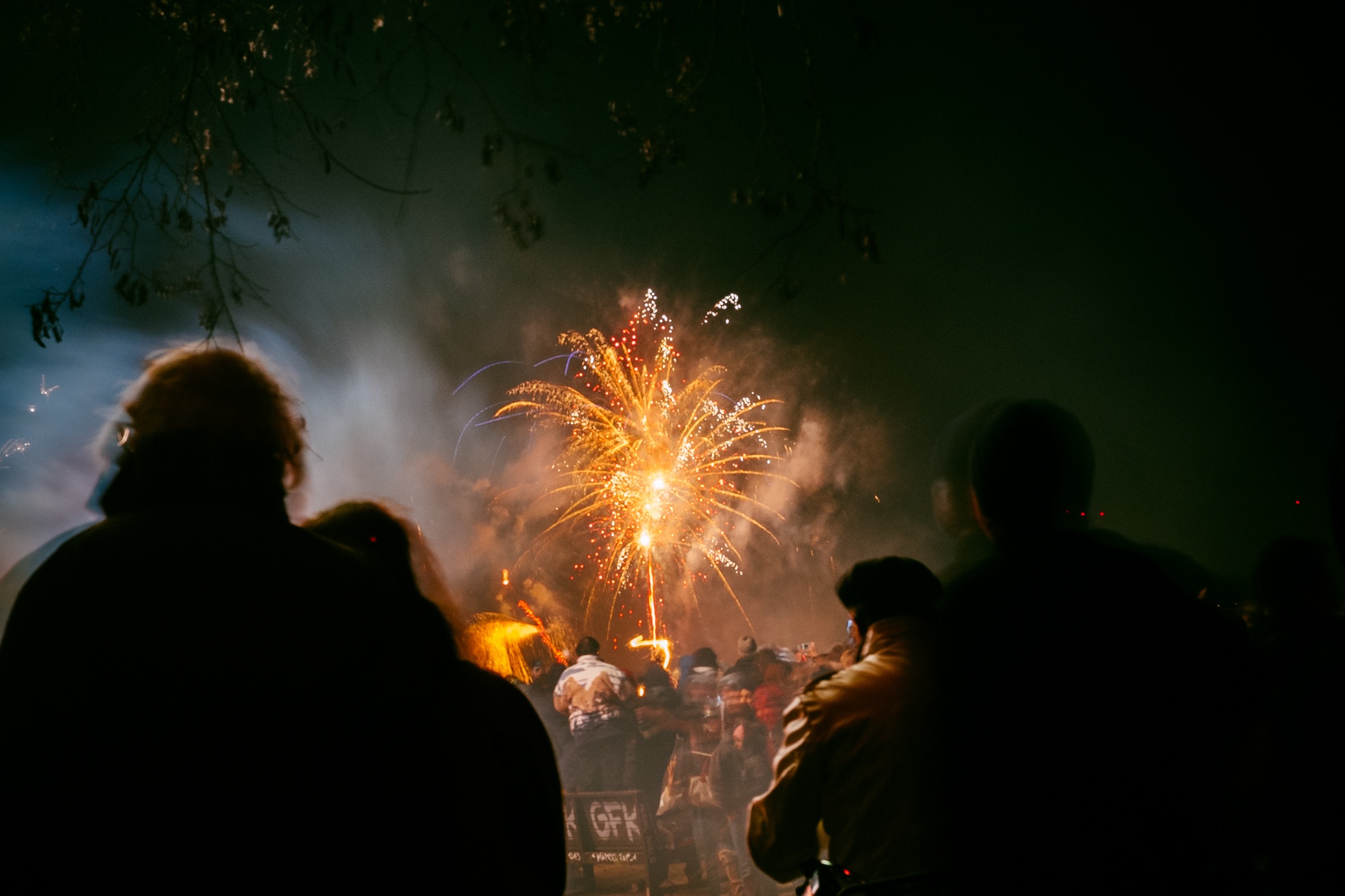 People standing in the dark watching fireworks.