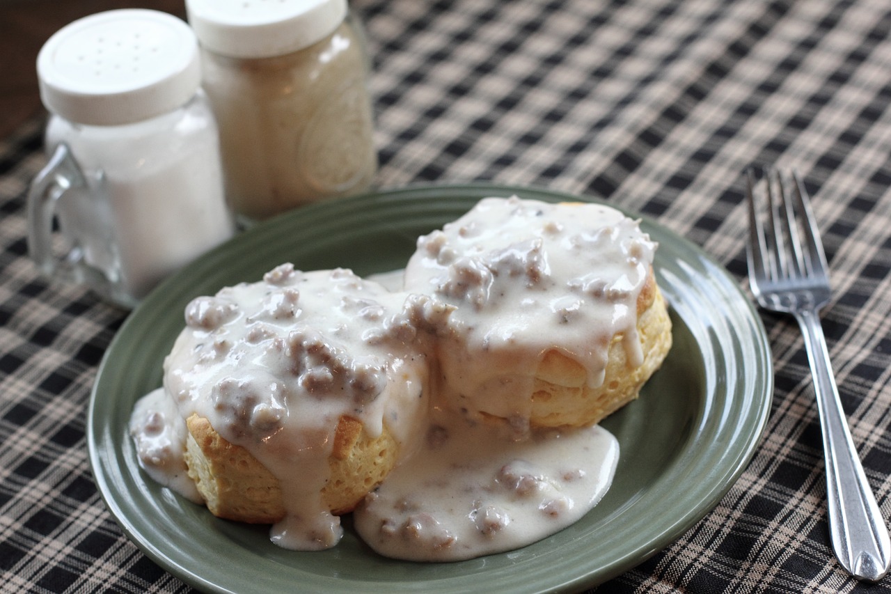 Two biscuits smothered in gravy with a fork.