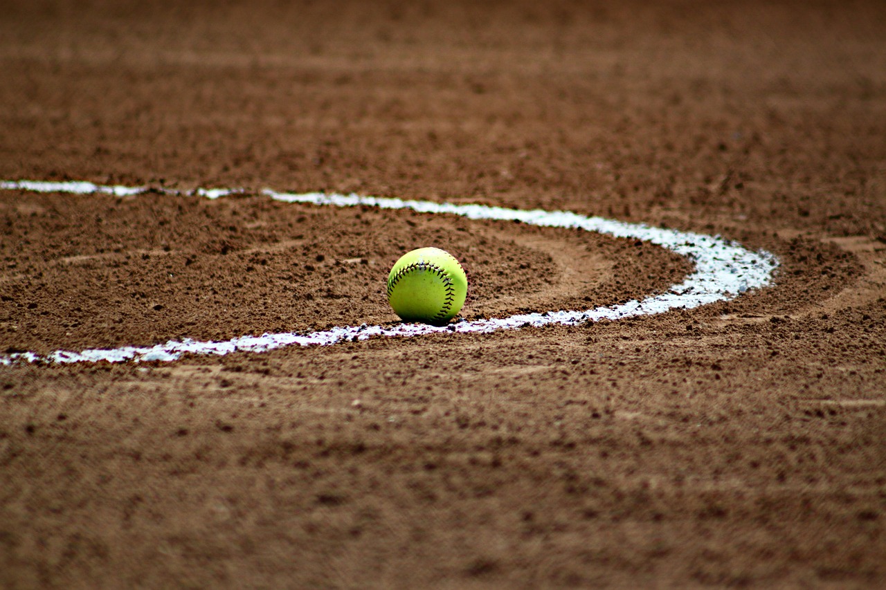Green softball sitting on a baseball field.